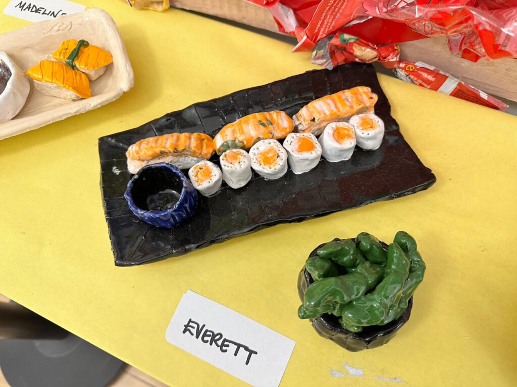 Ethical Culture 4th Grade ceramics projects (food sculptures) sit on display in hallway outside of art classroom.