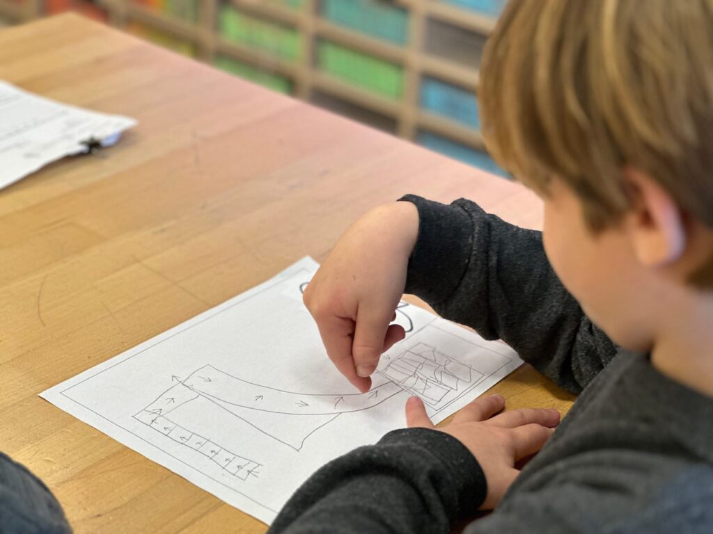 Fieldston Lower student works on his storyboard at desk in classroom.