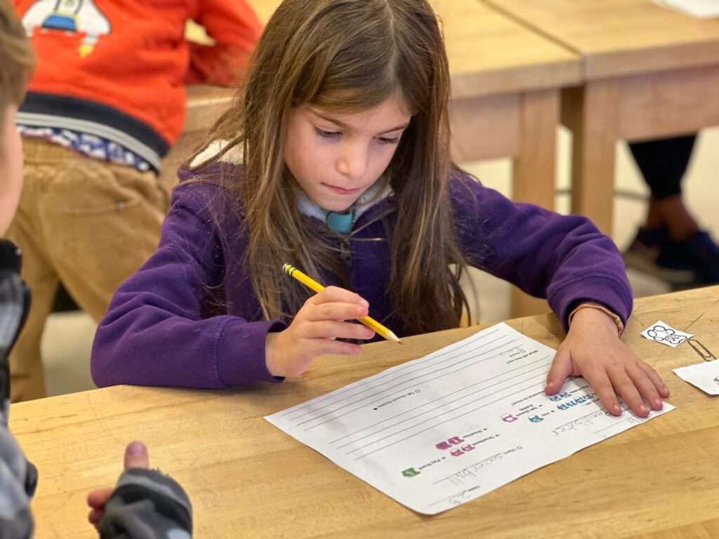 Fieldston Lower student works on her storyboard at desk in classroom.