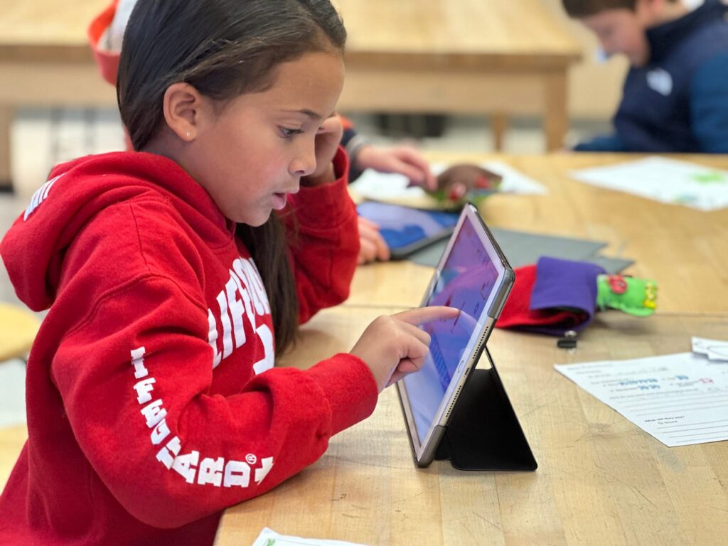Fieldston Lower student works on iPad while sitting at desk.