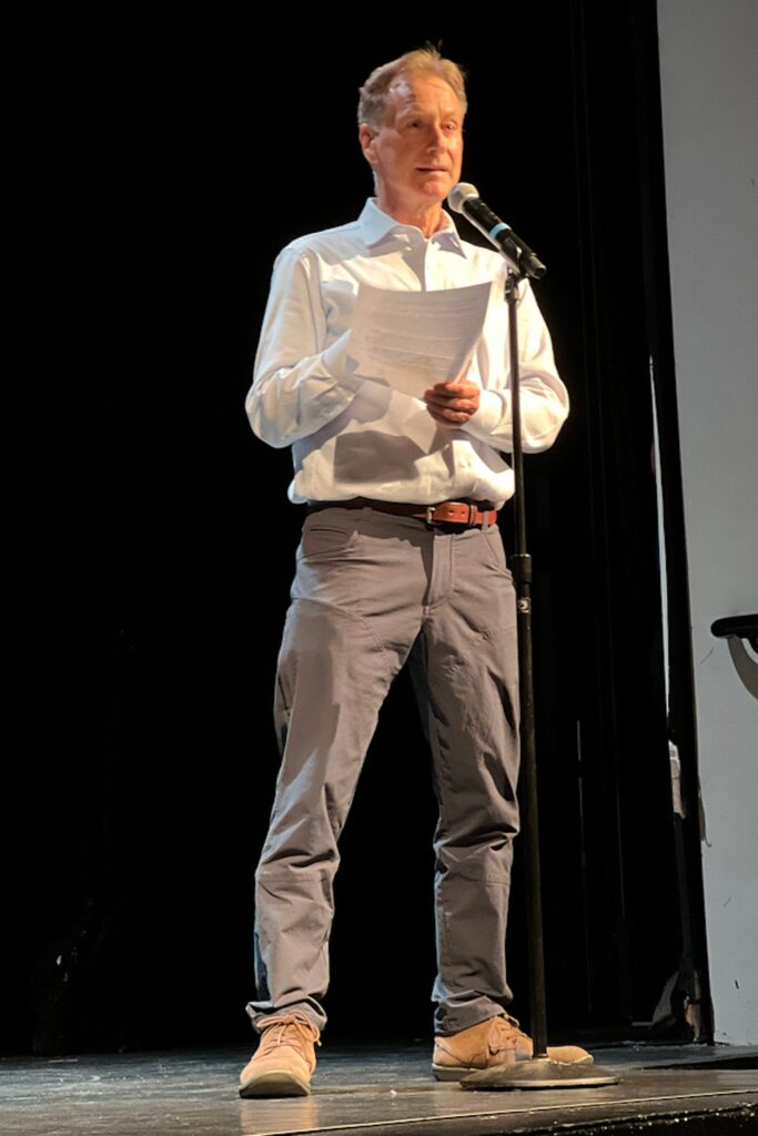 Theater and Dance Teacher Rob O'Neill introduces the performers on stage at the microphone.