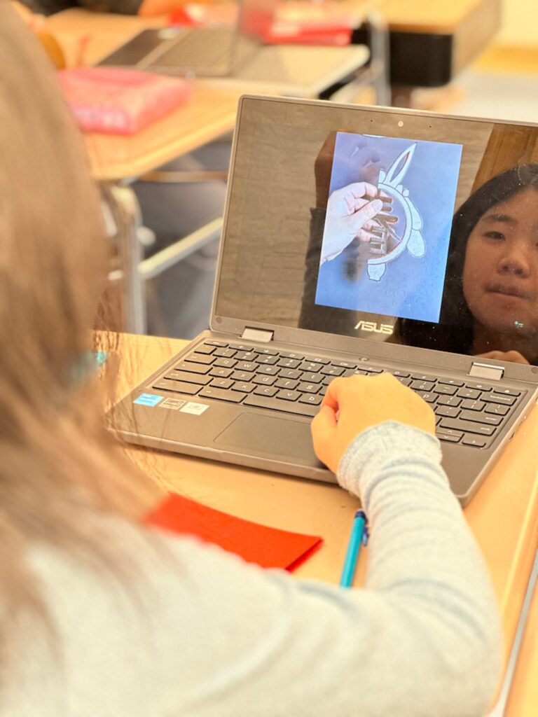 Student looks at computer tutorial about creating paper cutouts.