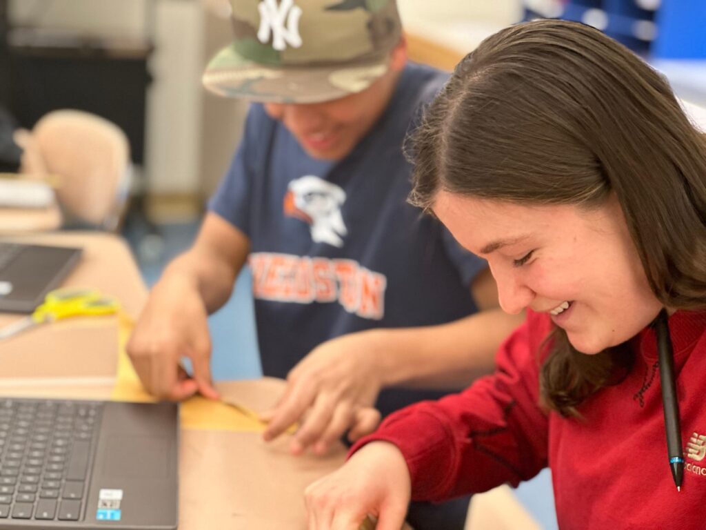 Student smiles as they fold rabbit origami.