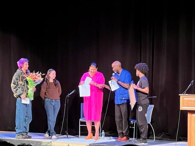 Dr. Elizabeth Alexander receiving presents on stage from Dr. Alwin Jones and several students