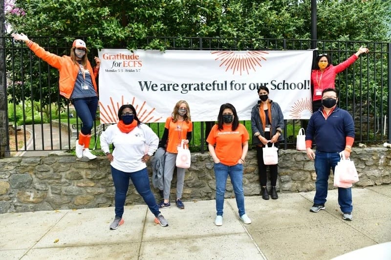 Giving day volunteers stand in front of sign on Fieldston campus
