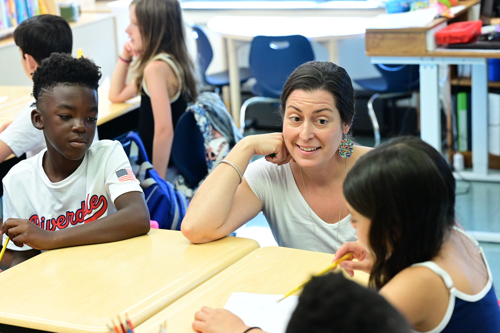 Fieldston Lower teacher guides students sitting at desks. 