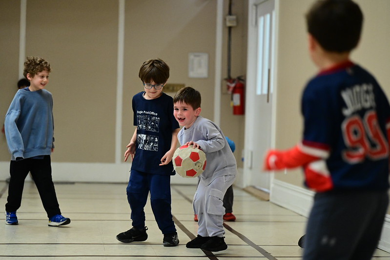 Students play basketball together indoors during recess.