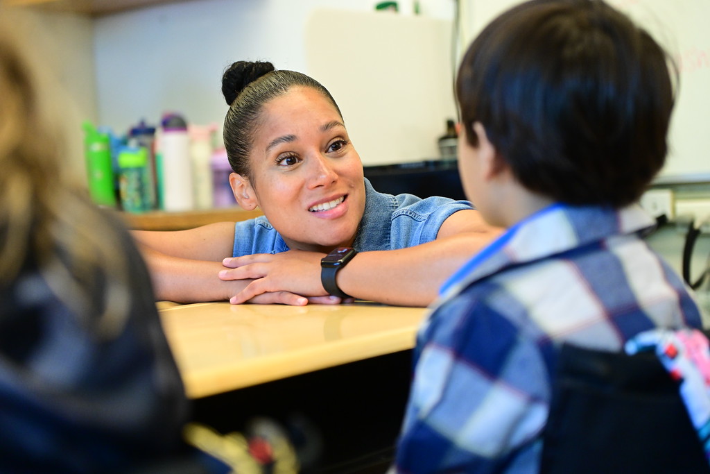 Fieldston Lower teacher guides student sitting at a desk. 