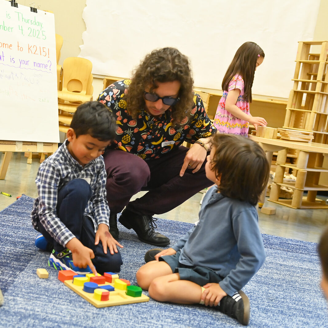 Ethical teacher guides students while they play with blocks on the carpet. 
