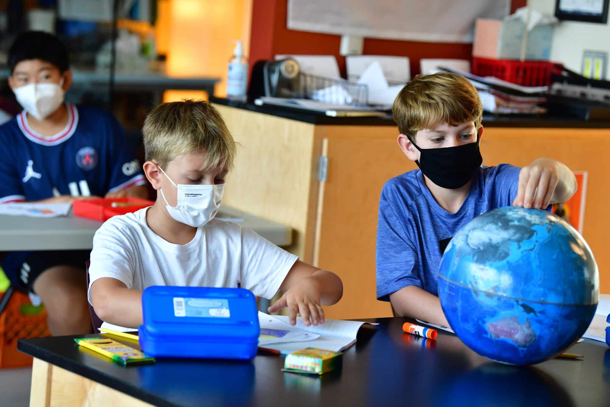 two students inspect a globe scaled 1